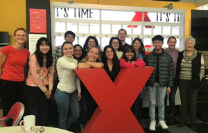 Codsi stands with students around a large red "X" sign. 