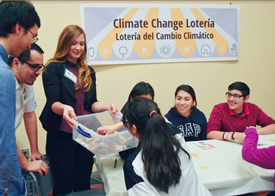 Drury hands out a box to a group of youth in a classroom playing a learning game about climate change.