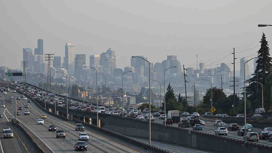 Photo of downtown seattle and interstate 5 with heavy traffic. A haze of pollution obscures the buildings of downtown.