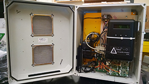 The inside of an air monitor.  White metal box with hinged opening that displays the wires inside.