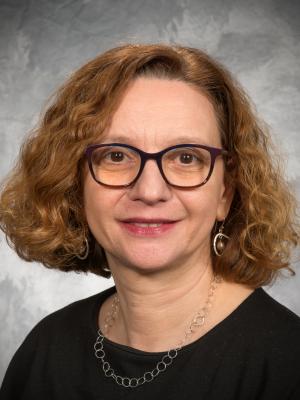 Dr Guizzetti, a middle-aged white woman with curly red hair and dark framed glasses