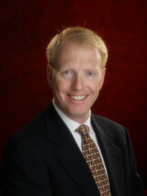 Dr Tubby, a middle-aged white man with short red hair wearing a suit