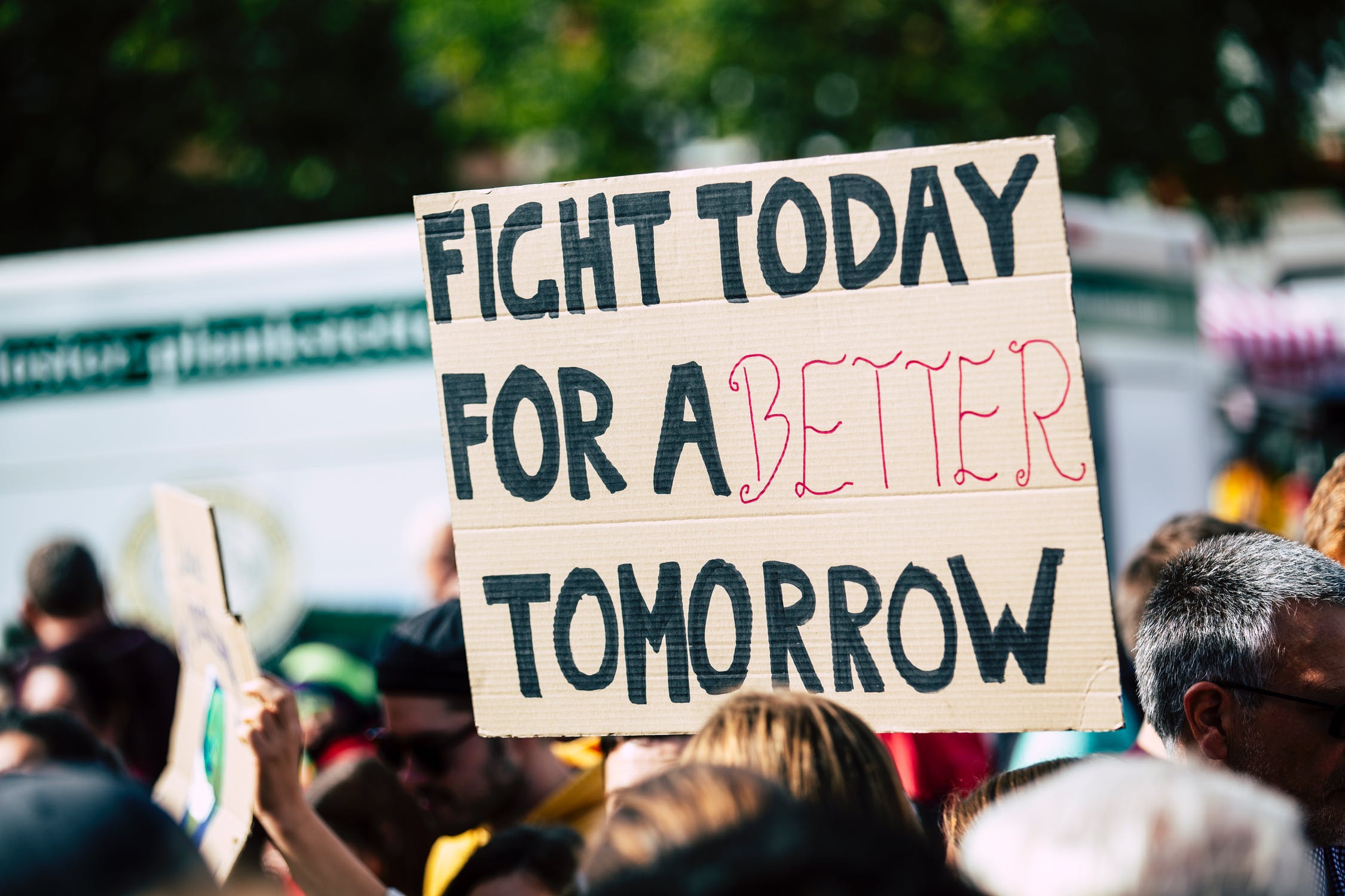 a student in a group holding a sign reading "fight today for a better tomorrow"