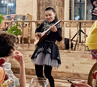 A young woman in black plays a traditional Kyrgyz instrument.