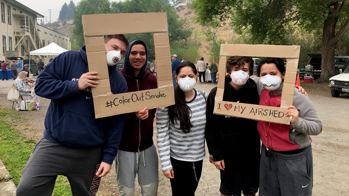 Teenagers pose with airmasks that they decorated.