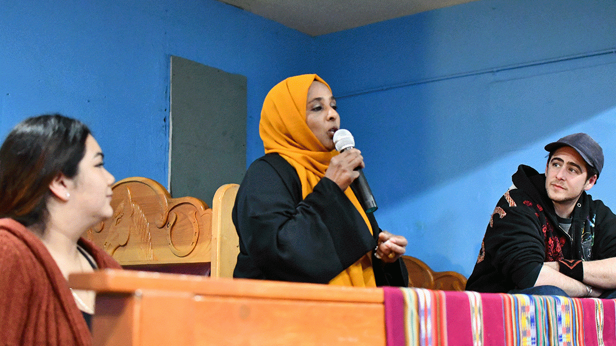 A woman in a saffron headscarf holds a microphone as she tells her story of living in the Duwamish Valley