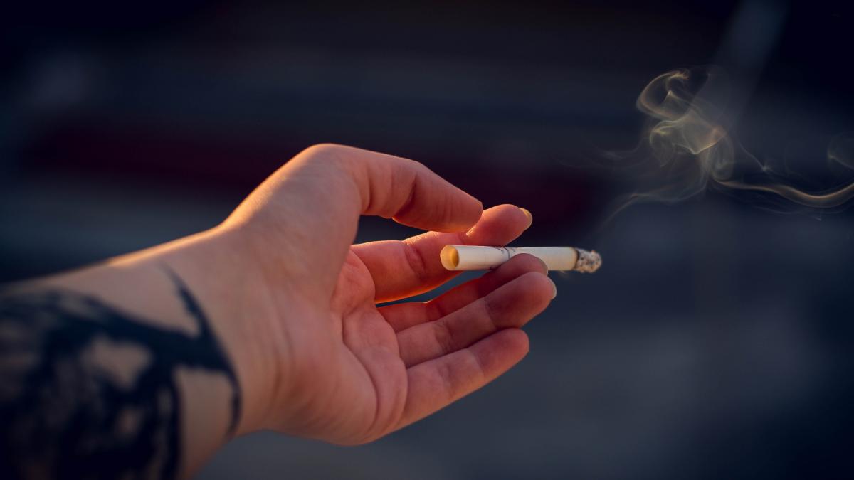A hand holding a lit cigarette.