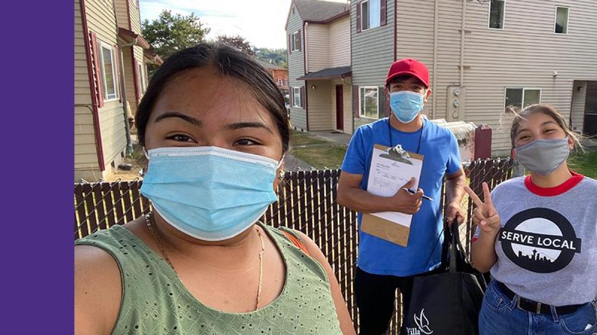 Photo of three Latinx teens wearing covid masks on a resident's porch while conducting a door to door survey 