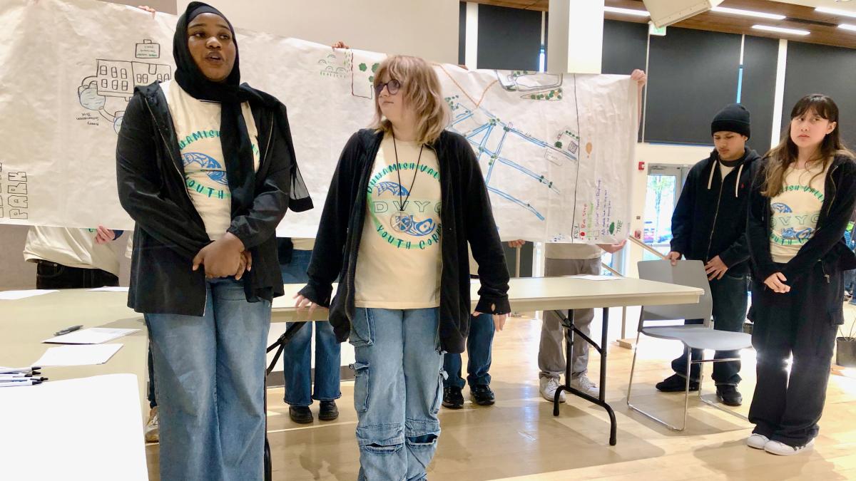 Duwamish Valley Youth Corps students stand in front of a hand-drawn map pf community resilience