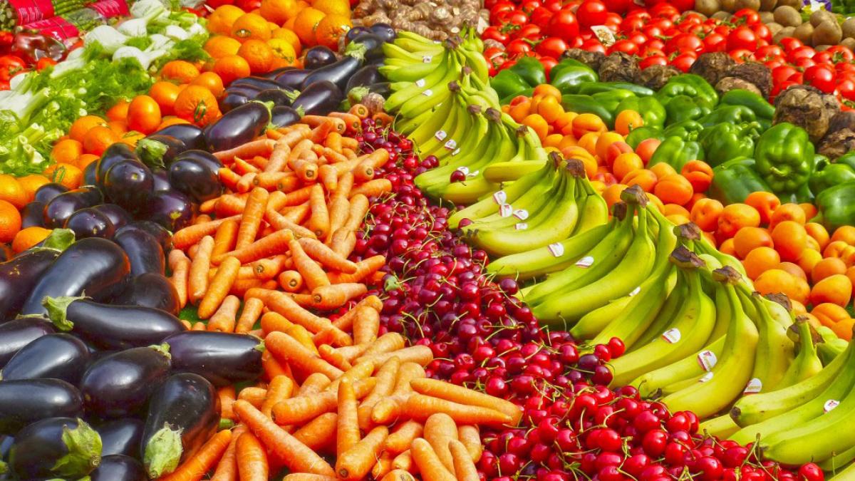 Fruits and vegetables sit in colorful rows on a table.