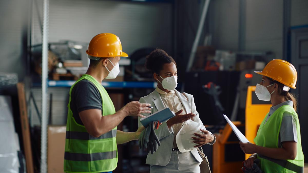 Three workers discuss at a workplace