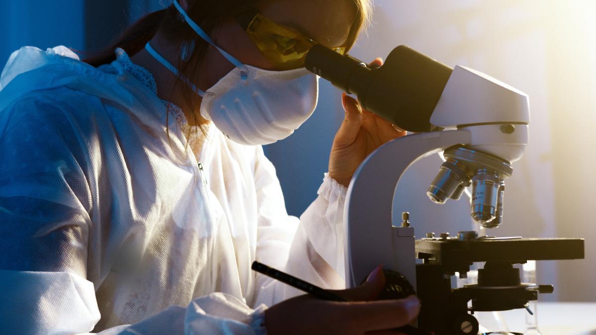 woman looking into microscope