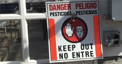Vista cercana de la señal de advertencia “PELIGRO, pesticidas, NO ENTRE”.