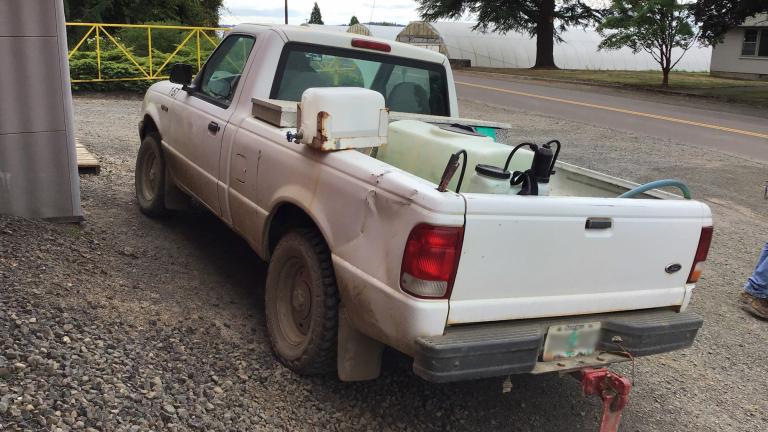 Image of a company pick-up truck with pesticide containers in back