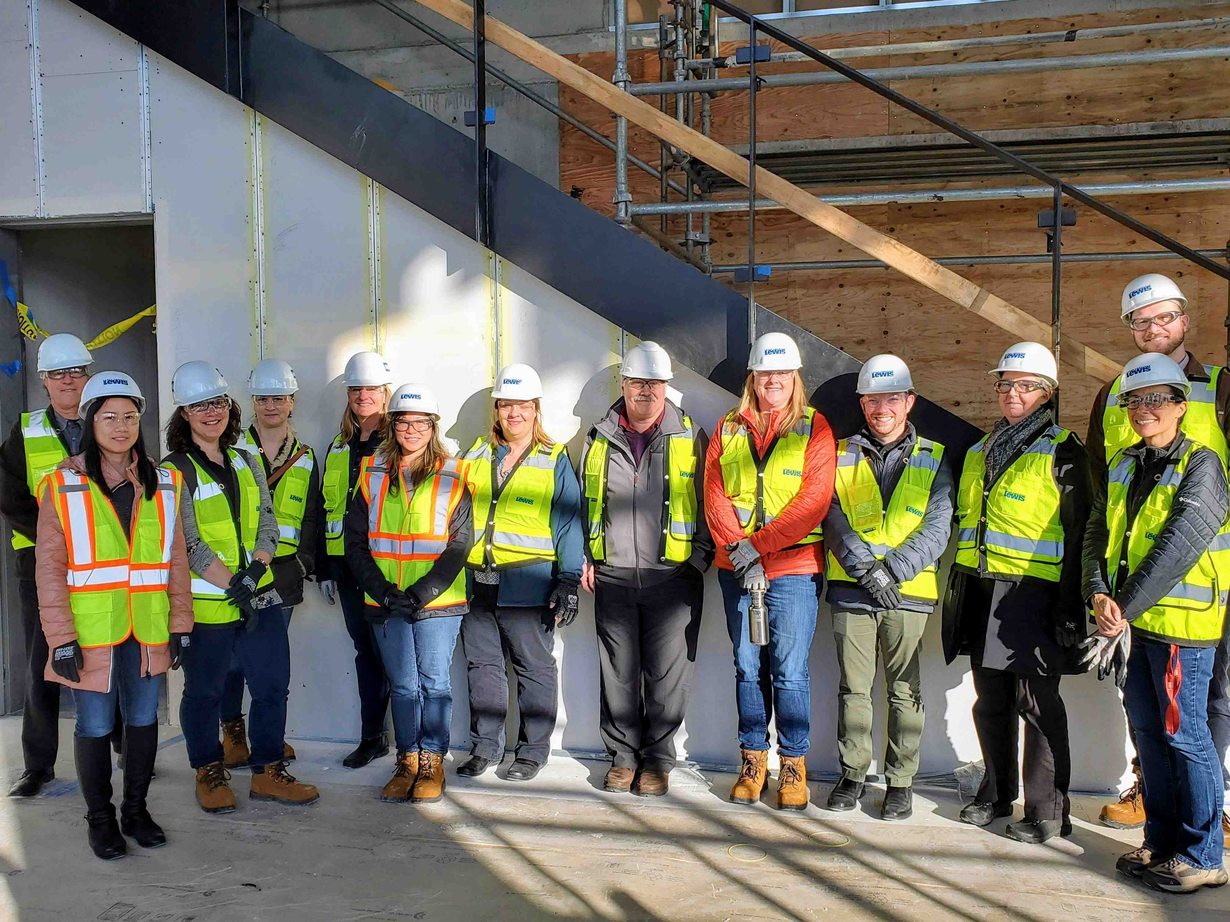 A group of people in hardhats pose at a construction site.