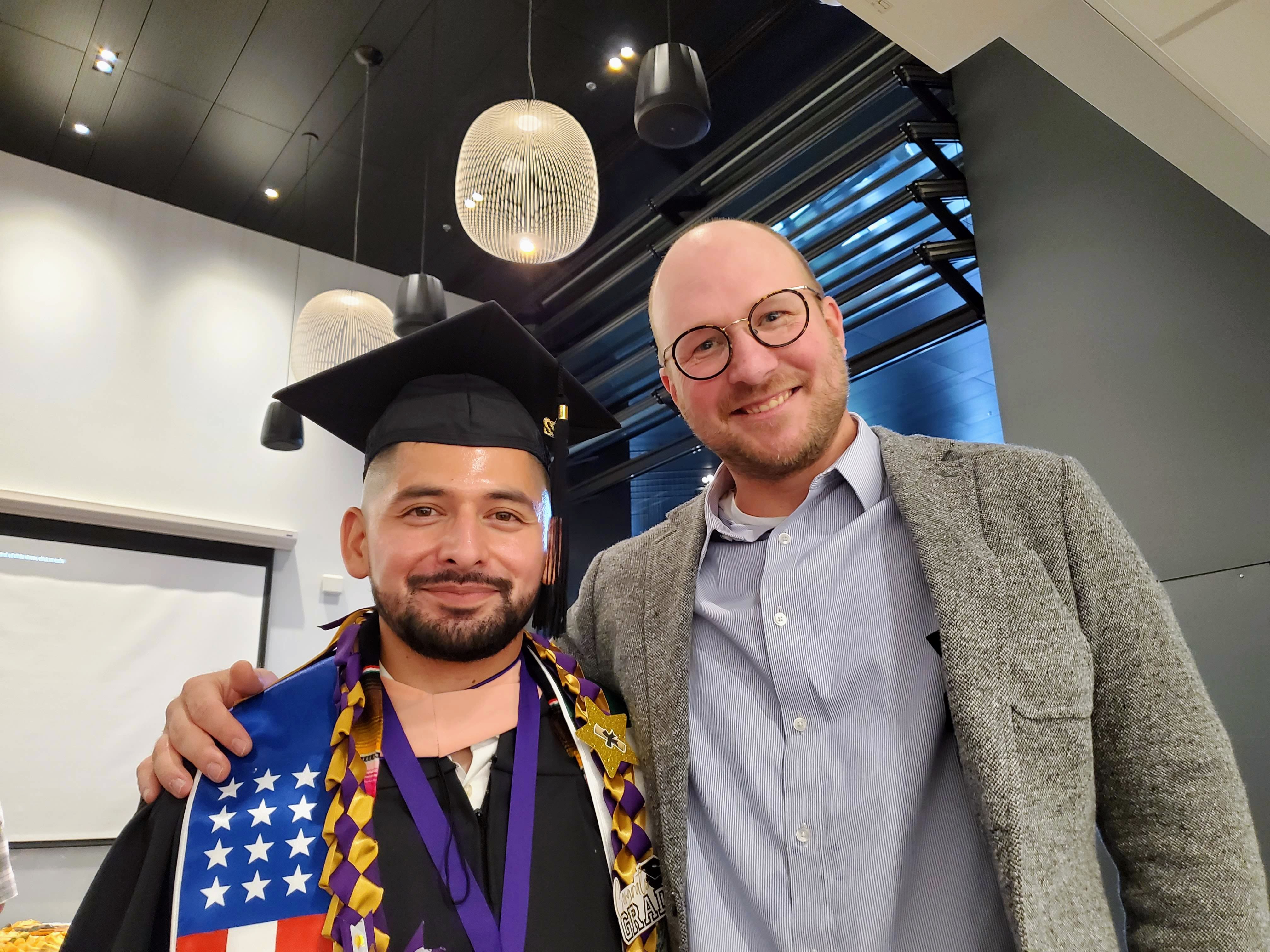 A graduate student poses next to his mentor at the DEOHS graduation reception.
