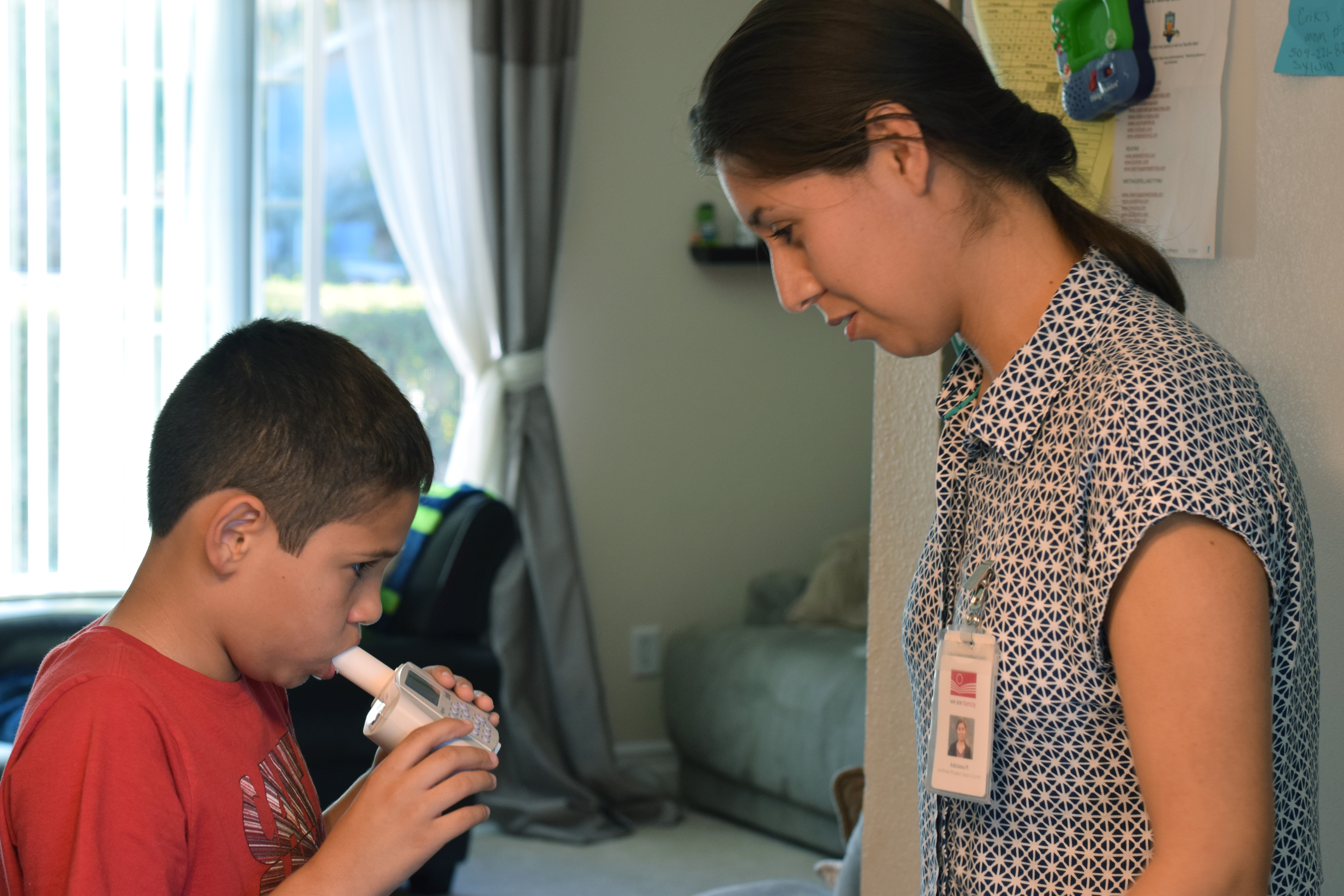 Adriana Perez of Yakima Valley Farmworkers Clinic uses a spirometer with a study participant to measure lung function during a home visit.
