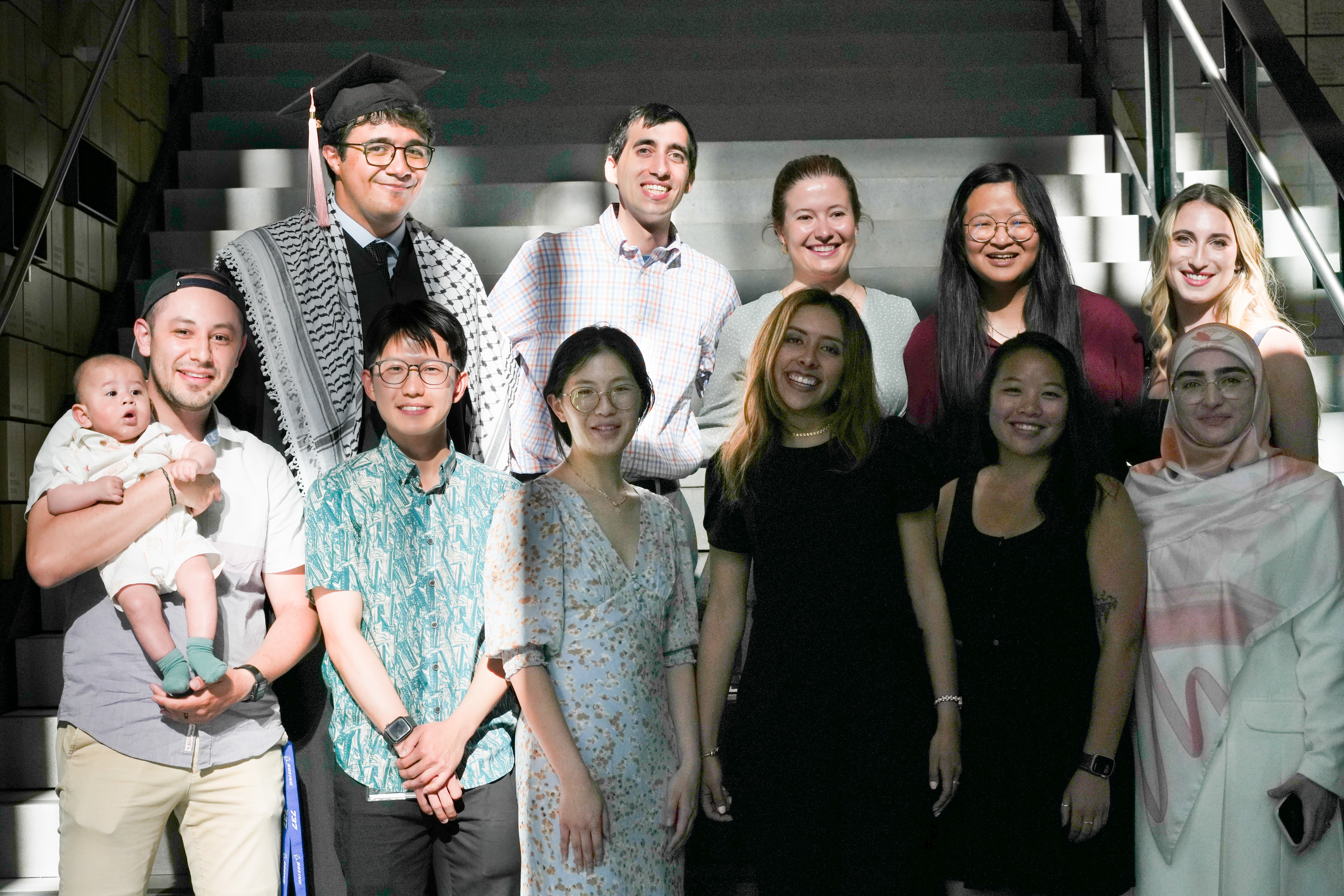 A group of Master’s students stand on the stairs of the Hans Rosling Center, smiling, celebrating their graduation. 