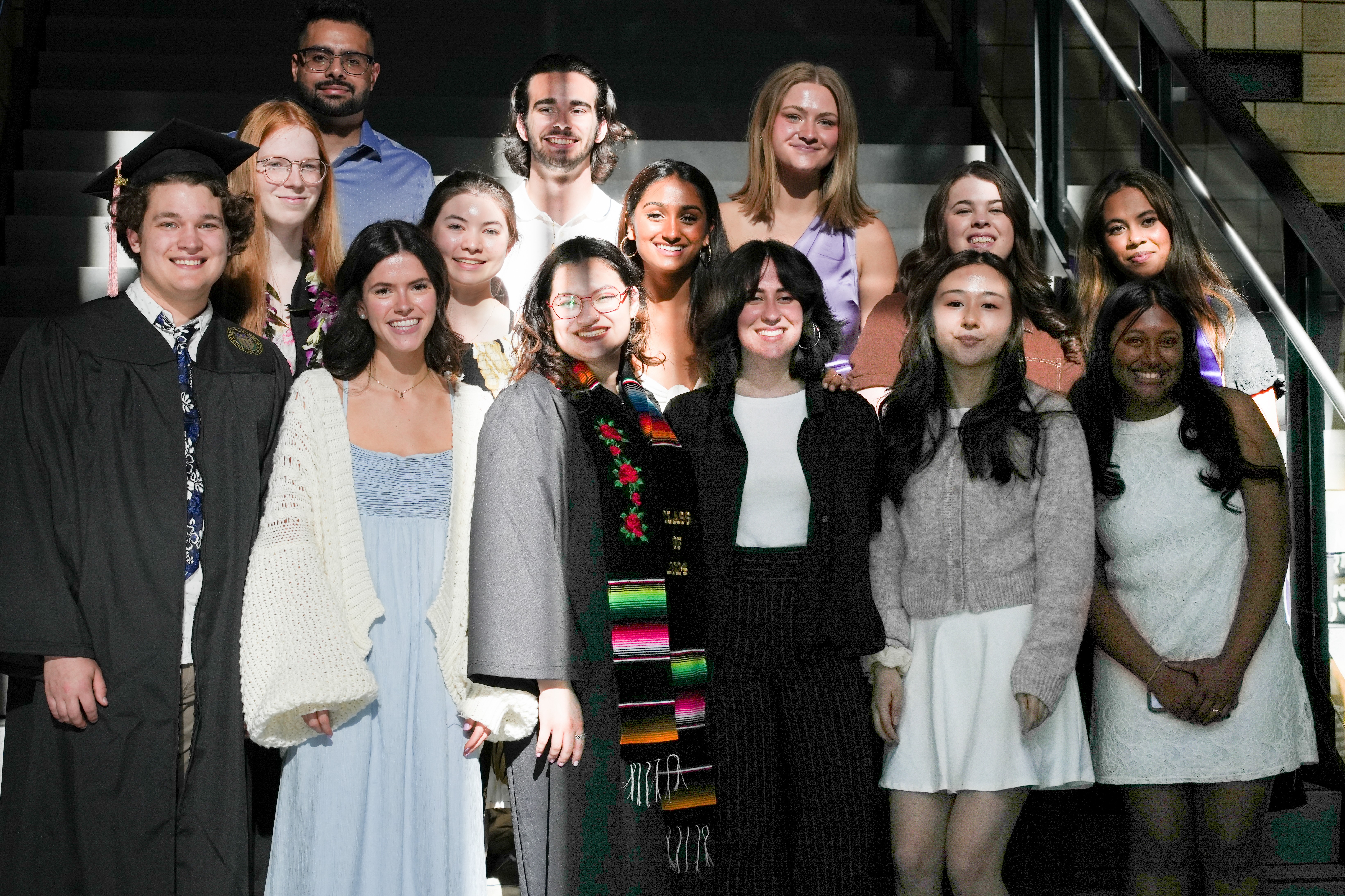 A group of undergraduates stands on the stairs of the Hans Rosling building, smiling at the camera. 