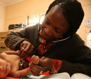 A doctor with a stethscope listens to a baby's chest.