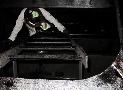 Photo showing Liu from above climbing up stairs on a vessel with hard hat on.