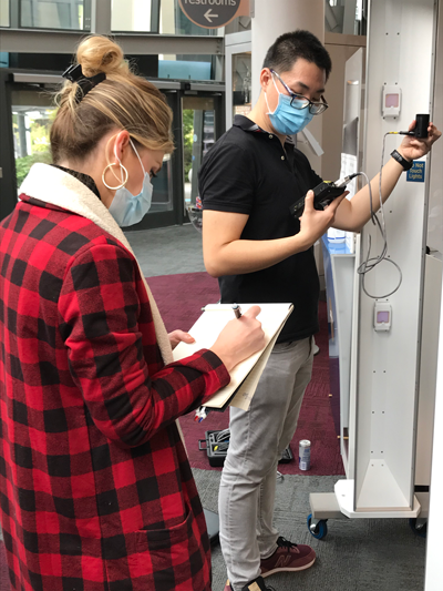 A man and a woman wearing masks measure ultraviolet light emissions.