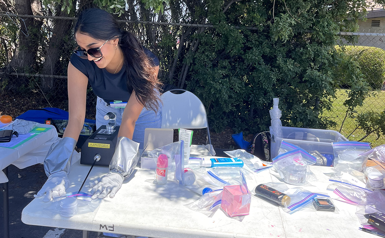 A woman in sunglasses sets up supplies on a table outdoors.