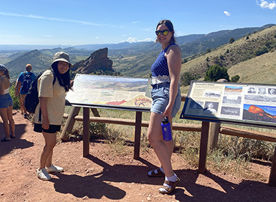 Two women stand at an overlook of mountains in Colorado.