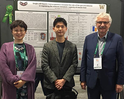 Three people stand in front of a poster with Joe Lim in middle.