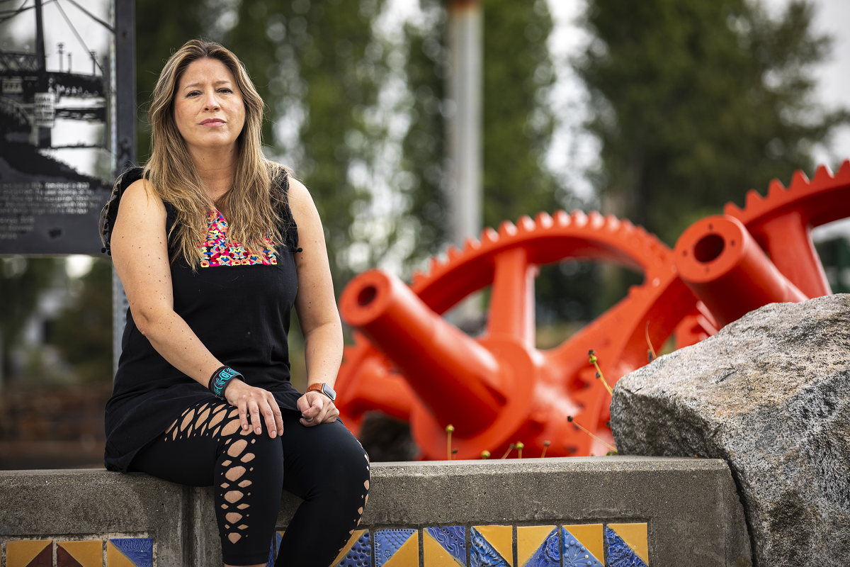 Maribel Pastor sits on a bench in front of a sculpture in the Duwamish Valley.