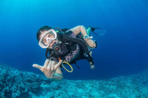Codsi scuba diving and giving a hang-loose hand sign.