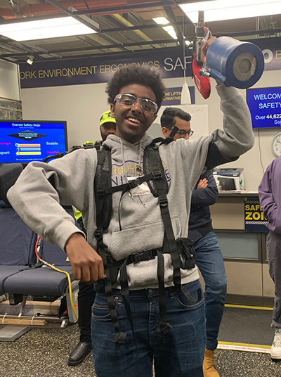 A student from the Brotherhood Initiative holds up a fire extinguisher on a visit to Boeing.