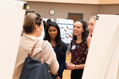Errett talking with three students at a poster session.