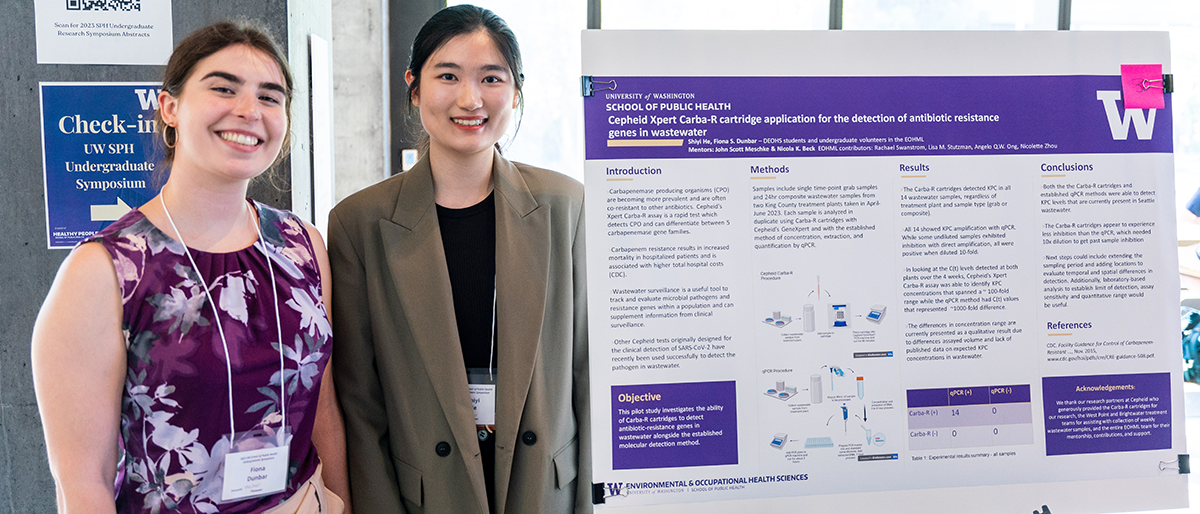 Fiona Dunbar and Shiyi He stand in front of their poster at the symposium.