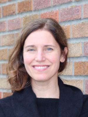 Headshot of Christine Loftus standing in front of a brick wall.