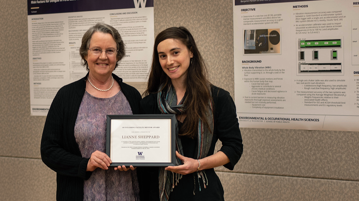 Photo of two women standing together holding a framed award certificate.