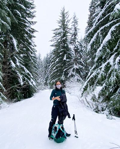A woman in snowshoes stands in a snowy forest.