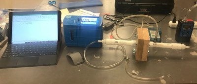 A lab setup with PVC pipe and pressure sensors for testing the pressure drop across a material.