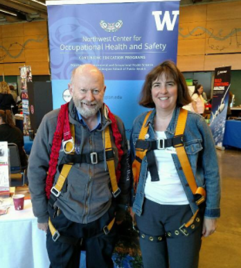 A man and a woman wear safety harnesses at a conference.
