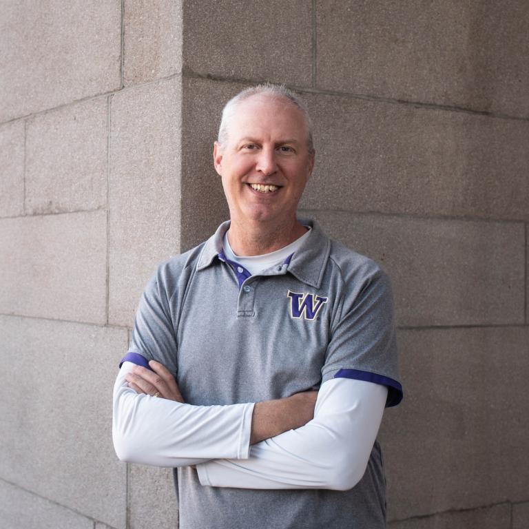 Photo of Dan Poux, a man with white skin, grey hair and a grey and white shirt. 