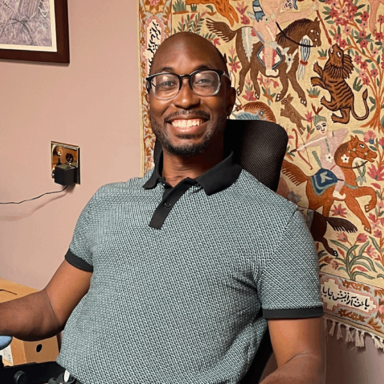Alawode sits in an office in a clinic with a tapestry behind him. 