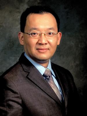 Jia-Hua Lin, a middle-aged Asian man with small glasses wearing a suit