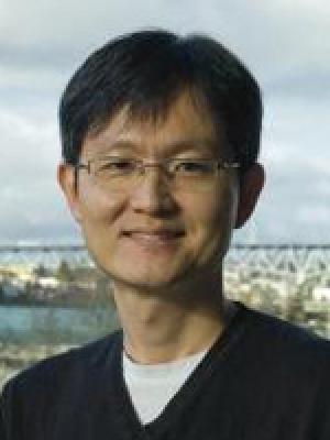 A thin middle-aged Asian man with clear framed glasses 
