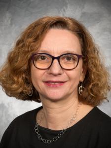 Dr Guizzetti, a middle-aged white woman with curly red hair and dark framed glasses