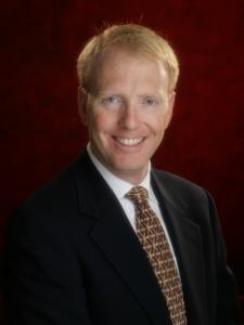 Dr Tubby, a middle-aged white man with short red hair wearing a suit