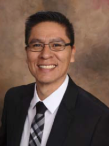 Dr Yazzie, a middle-aged Native American man with short bushy hair wearing a suit