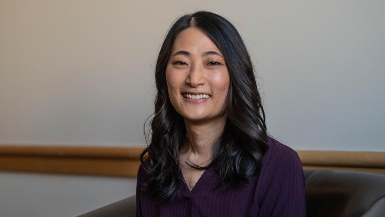 Photo of Esther Min sitting in a chair smiling.