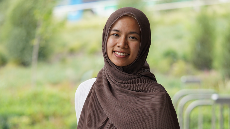 Closeup photo of Everetta Rasyid smiling, wearing a brown hijab outside.