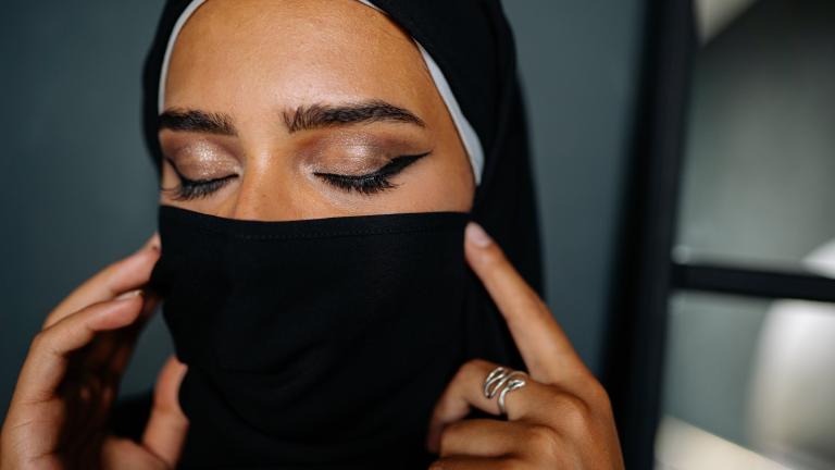 A woman in a hijab with eyes closed wearing traditional eyeliner.