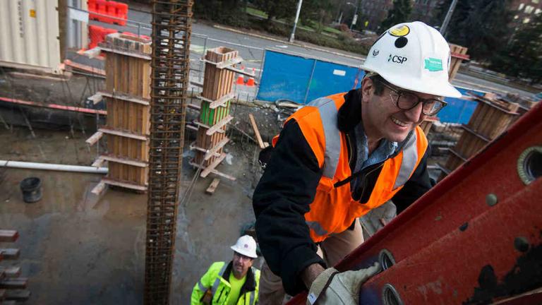 Faculty climbing ladder on worksite